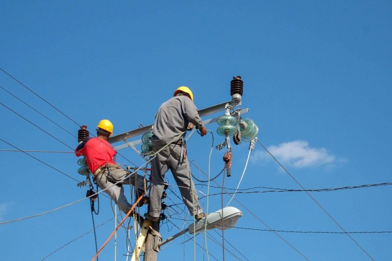 low-angle-shot-electric-linemen-working-pole-1-scaled.jpg